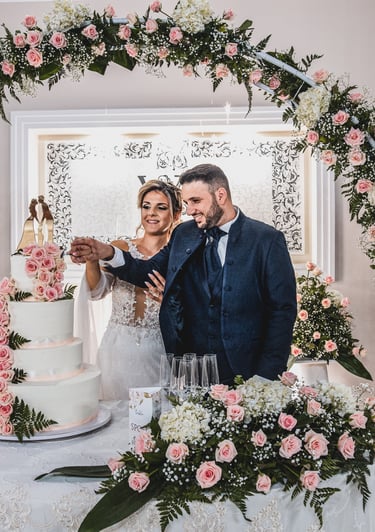 sposi al taglio della torta con addobbi floreali