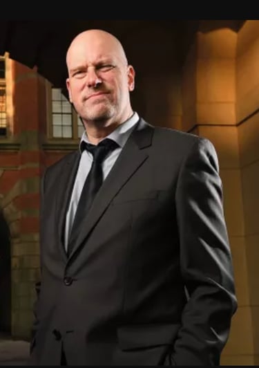 David Gillborn in a suit and tie standing in front of a building