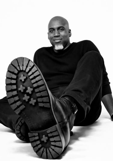 Lee A Jones in all black sitting on the floor with black boots