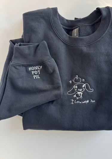 a black sweatshirt with a child's drawing embroidered on it