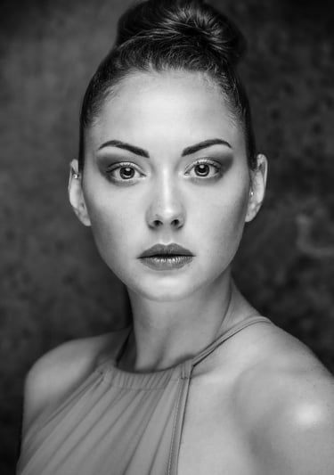 Black and white fine-art portrait of a woman in studio lighting with a neutral expression.