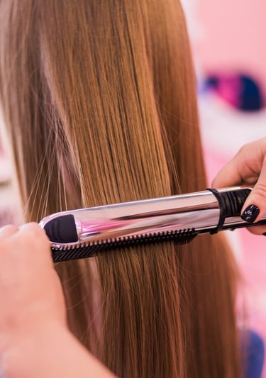 a woman is straightening her hair with a hair straightener