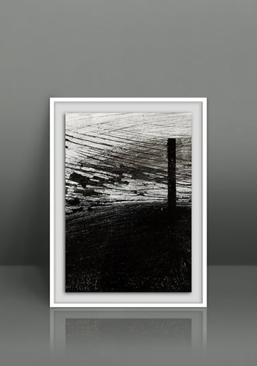 Framed minimalist black and white abstract art print with textured brushstrokes on a gray wall.