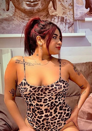 Chica colombiana en body animal print sobre el sofá mostrando su escote