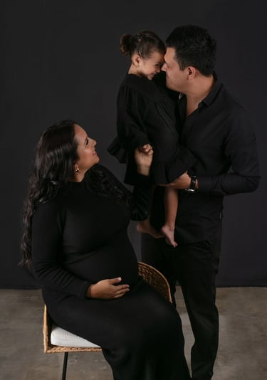 mamá embarazada, papá sosteniendo a su hija sonriendo en el set de fotografía