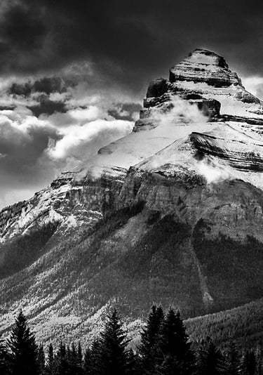 Charity Mountain in the Canadian Rocky Mountains, showcasing it's rugged snow covering and a dramtic sky