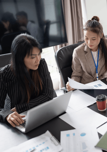 two women sitting at a table with papers and papers