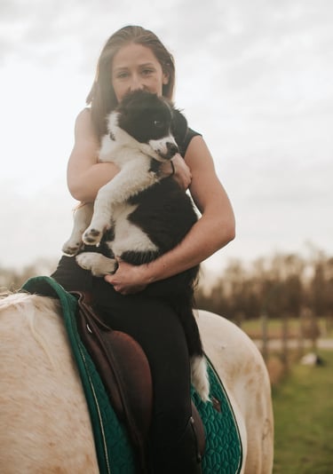 portrait d'une psychologue cavaliere avec son chiot dans les bras