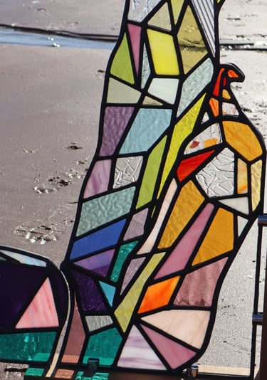Full Sized Stained Glass Woman. Photograph is taken on a beach at low tide. Art work by Laura Kriefman