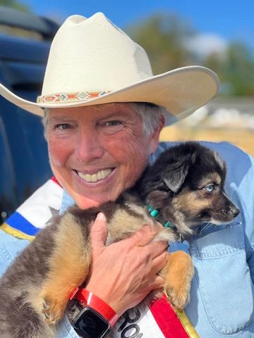 Jen Vrana in a white cowgirl hat holding a puppy