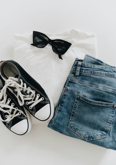 A white T-shirt, blue jeans, black sunglasses, and black sneakers with white shoelaces