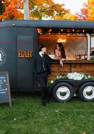 a bride and groom standing in front of our mobile trailer bar