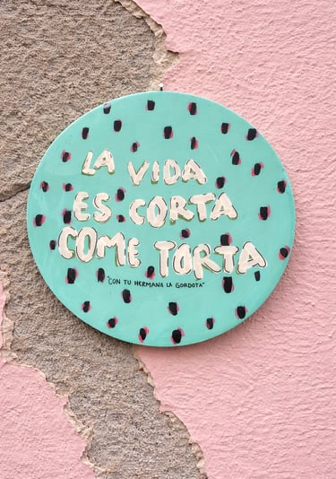 Letrero redondo de color turquesa pintado a mano sobre una pared rosa 