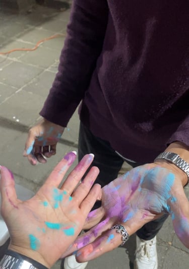 Manos cubiertas de pintura en polvo vibrante de color azul, morado y rosa 