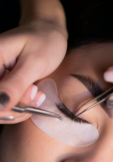 Lashista aplicando extensiones de pestañas técnica clásica en cabina profesional de belleza.