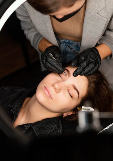 Profesional de cejas que da forma a las cejas con pinzas para una clienta en salón de bellleza