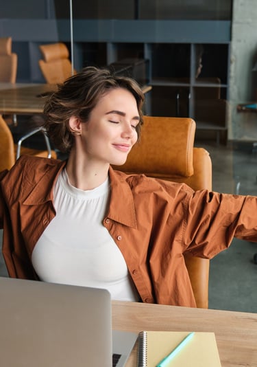 Mujer relajándose durante su jornada de home office, practicando una pausa de bienestar laboral 