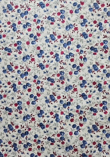 Vintage calico fabric with a ditsy floral print featuring small blue and pink roses on a white background.