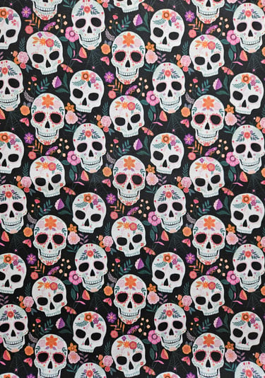 Sugar skull pattern fabric featuring Day of the Dead calaveras with colorful floral decorations on black.