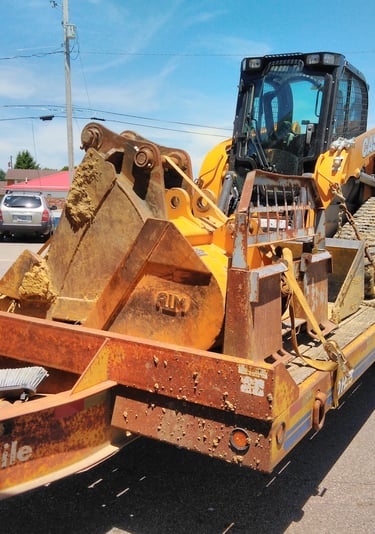 a tractor trailer with a loader on it