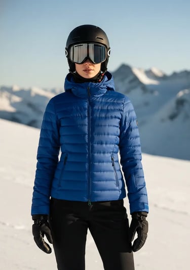 Front view of a woman wearing a stylish sapphire blue ski jacket paired with black ski pants and a h