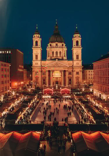 St. Stephen’s Basilica Christmas Market in Budapest at night, featuring glowing stalls, festive crow