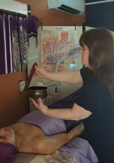 woman using a singing bowl to administer reiki healing energy to client