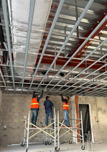 Trabajadores HVAC sobre andamios instalando ductería residencial
