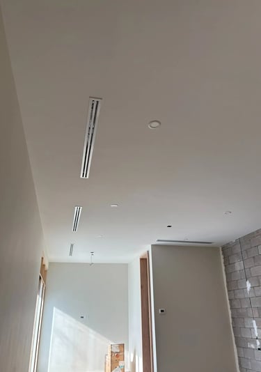 Construcción interior moderna con difusores lineales y iluminación empotrada en techo blanco