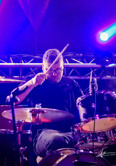 Arthur le batteur jouant de la batterie au festival du petit wood éclairé par des spots bleu.