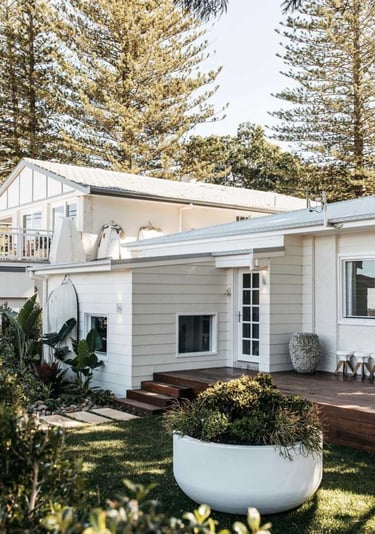 a white house with a large white planter and a large potted planter
