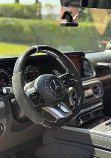 Mercedes-Benz AMG custom carbon fiber and alcantara steering wheel inside a luxury car interior.