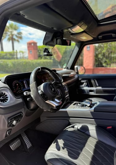 Luxury interior of a Mercedes-Benz G-Class with black leather seats and digital dashboard.