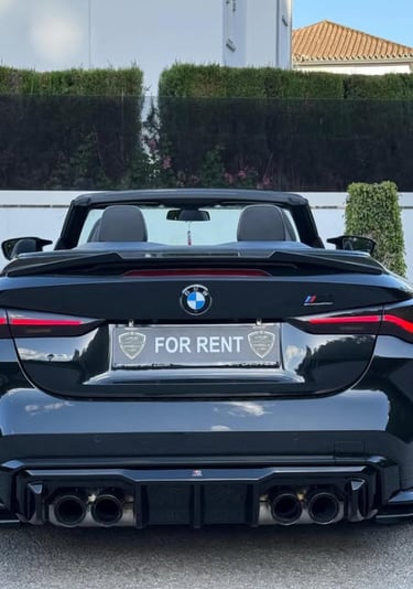 Rear view of a black BMW convertible luxury car for rent with quad exhaust and sporty diffuser.