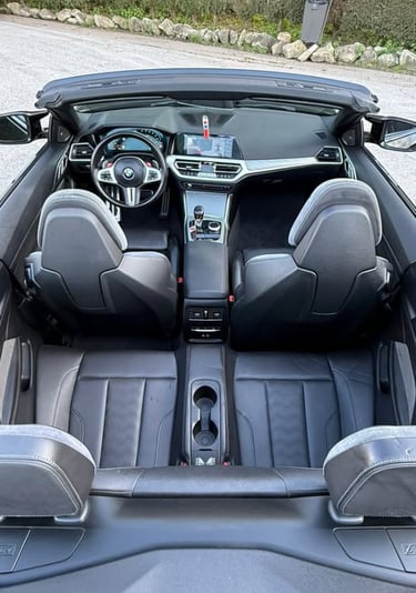 High-angle view of a luxury BMW convertible interior featuring black leather seats and modern dashboard.
