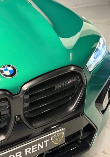 Close-up of a green BMW X5 M luxury SUV front grille with black accents for rent.