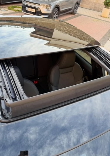 Top view of a luxury car with an open panoramic sunroof showing the black leather interior.