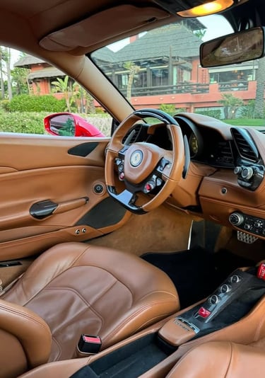 Luxury Ferrari interior with tan leather seats and carbon fiber trim on the dashboard and steering wheel.