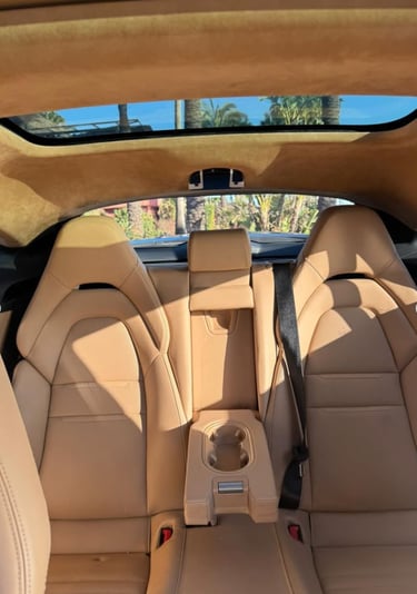 Luxury tan leather car interior showing rear bucket seats and panoramic sunroof.