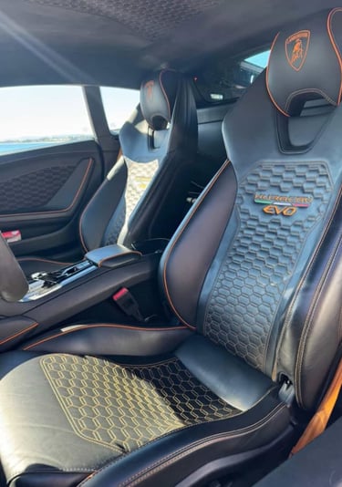Luxury interior of a Lamborghini Huracan EVO featuring black leather seats with orange stitching.