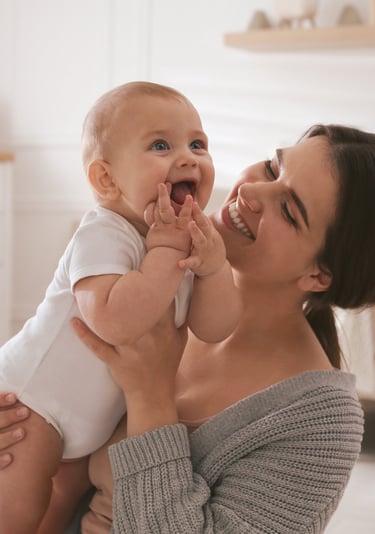 Anne kucağında gülümseyen bebek – evde bebek hemşireliği hizmeti