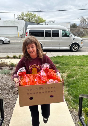 a woman holding a box of food in front of a van