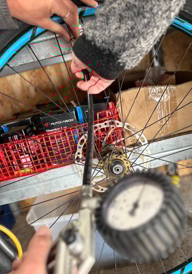 A person inflating a bicycle tire using an air compressor pump with a pressure gauge.