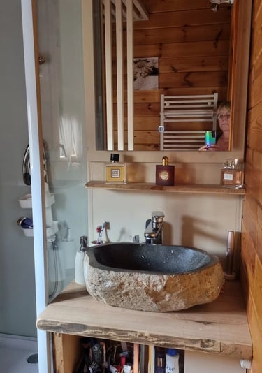 un lavabo de salle de bain avec une vasque en pierre et un meuble-lavabo en bois