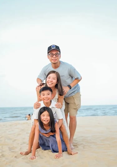 young asian family on a beach smiling with 2 young children