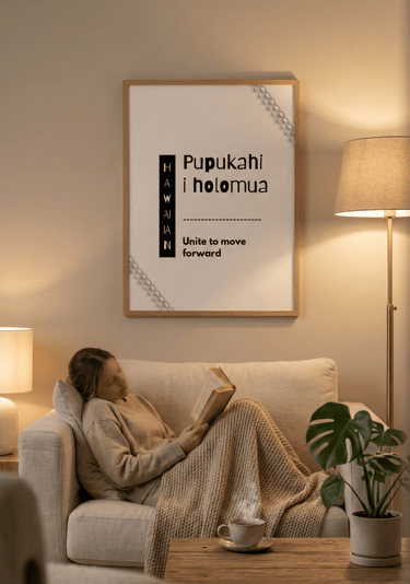 “Kulia i ka nuʻu” Hawaiian wall art above sofa in cozy evening living room with woman reading.