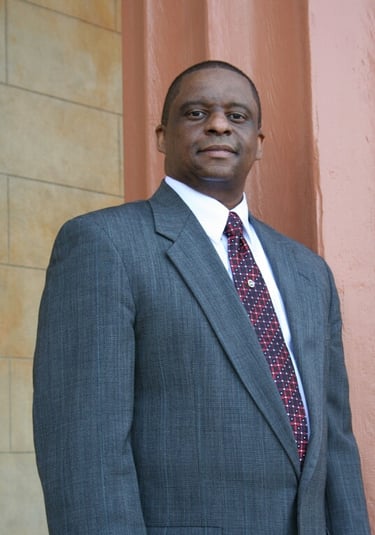 Mark T. Stewart in a suit and tie standing in front of the Old Courthouse