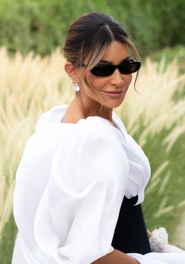 Close-up of woman in black and white gown with puffed sleeves and black sunglasses.