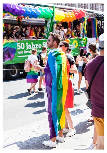 Ein Mann trägt eine Regenbogenflagge bei der Christopher Street Day Parade in Berlin.