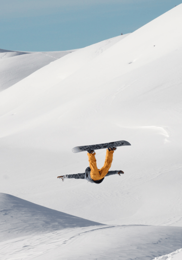 a snowboarder doing a trick on a snowy mountain